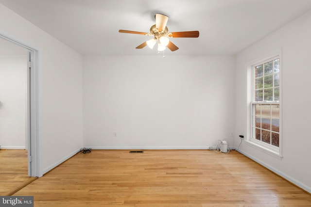 spare room with visible vents, a ceiling fan, light wood-style flooring, and baseboards