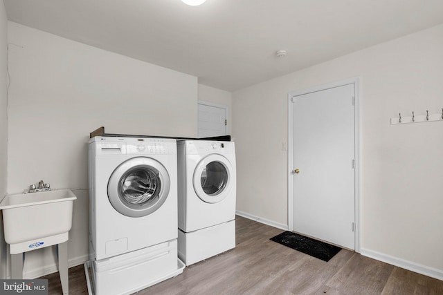 laundry room featuring laundry area, separate washer and dryer, wood finished floors, and baseboards