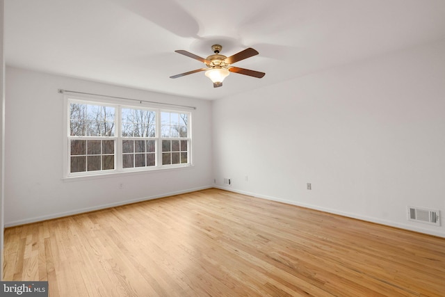 unfurnished room with ceiling fan, wood finished floors, visible vents, and baseboards