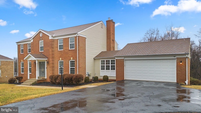 view of front of house with an attached garage, brick siding, driveway, a front lawn, and a chimney