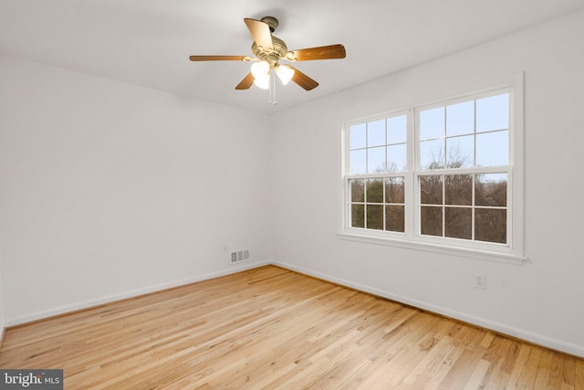 spare room featuring a ceiling fan, wood finished floors, visible vents, and baseboards