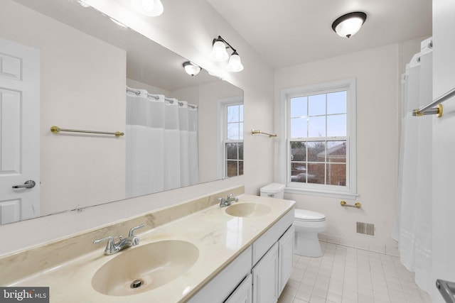 bathroom featuring visible vents, a sink, toilet, and double vanity