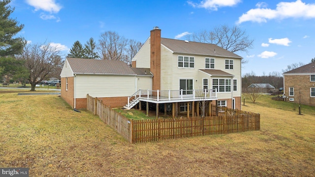 rear view of house with fence, stairway, a lawn, a wooden deck, and a chimney