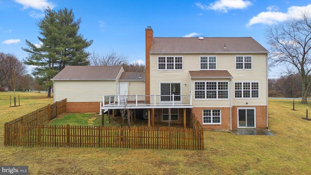 rear view of house featuring a deck, brick siding, a lawn, and a chimney