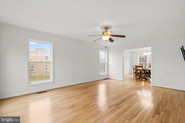 unfurnished living room with light wood-type flooring, visible vents, and a wealth of natural light