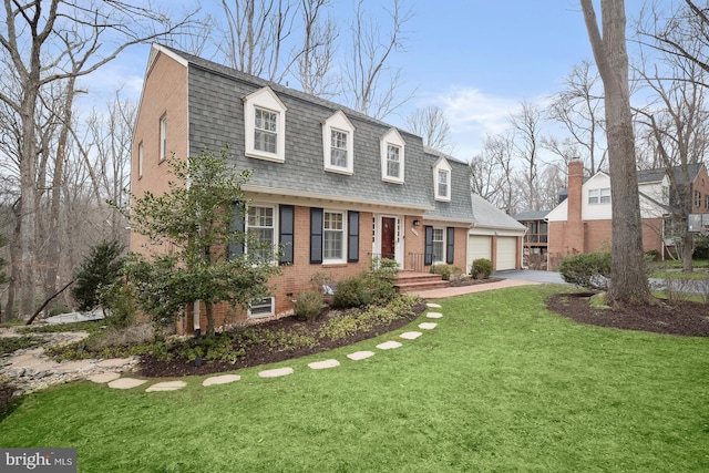 colonial inspired home with a shingled roof, concrete driveway, a gambrel roof, a front yard, and brick siding