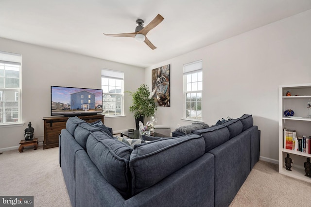 living area with a ceiling fan, light carpet, and baseboards