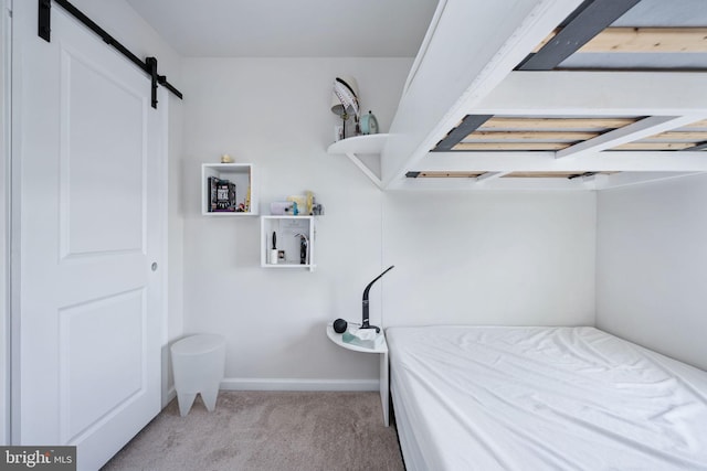 bedroom featuring light colored carpet, baseboards, and a barn door