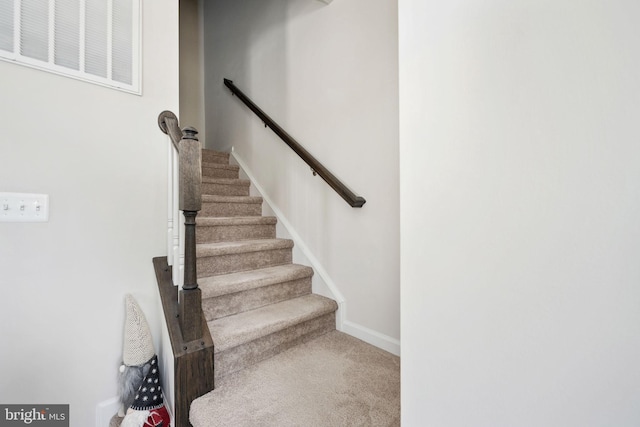 stairway featuring baseboards, visible vents, and carpet flooring