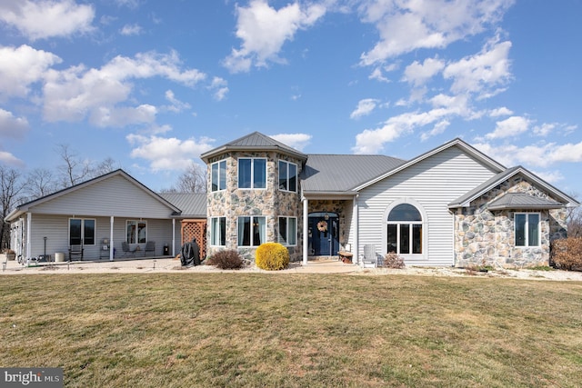 view of front of house with a front yard, stone siding, metal roof, and a standing seam roof