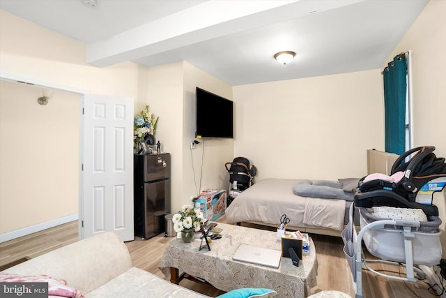 bedroom with wood finished floors, freestanding refrigerator, and baseboards