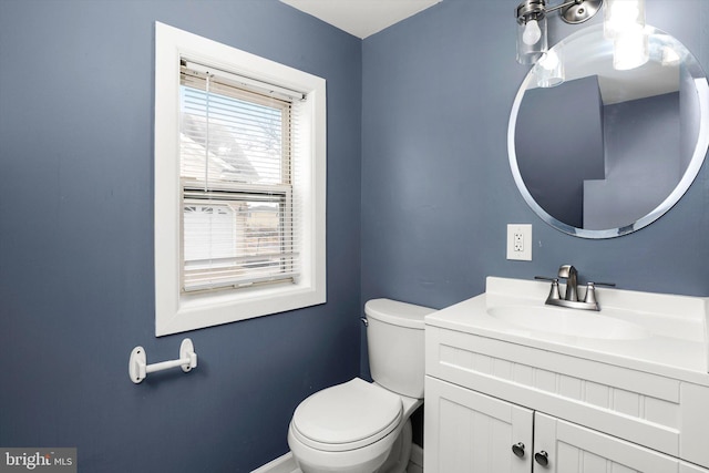 half bathroom featuring baseboards, vanity, and toilet