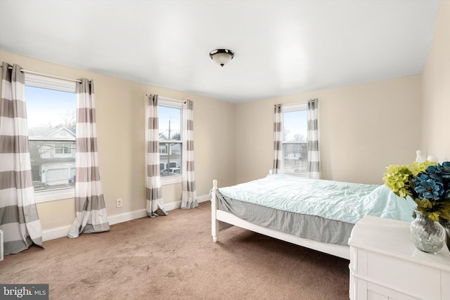 bedroom with light colored carpet, multiple windows, and baseboards