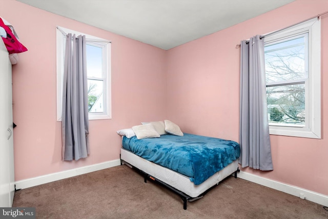 carpeted bedroom with multiple windows and baseboards