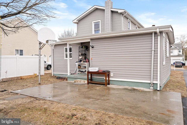 rear view of house featuring a chimney, a patio area, and fence