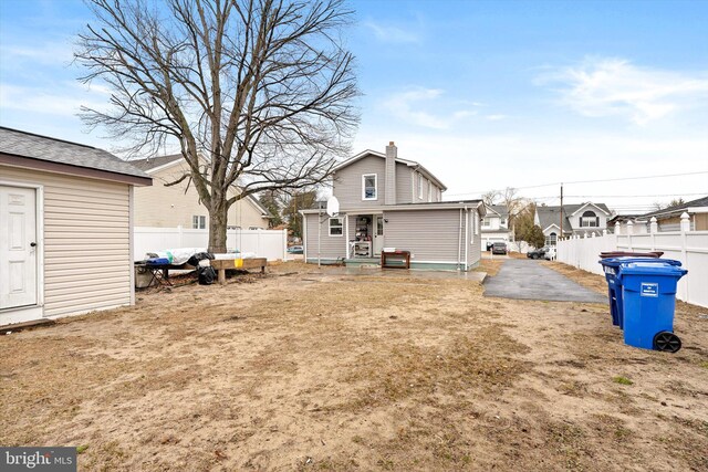 rear view of property featuring a residential view, fence, and a chimney