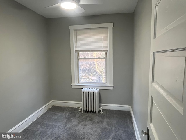 spare room with ceiling fan, radiator heating unit, dark carpet, and baseboards