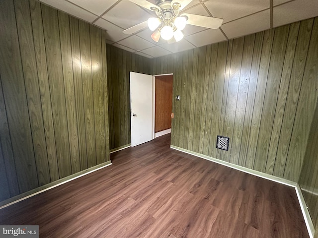 spare room featuring wood walls, ceiling fan, baseboards, and wood finished floors