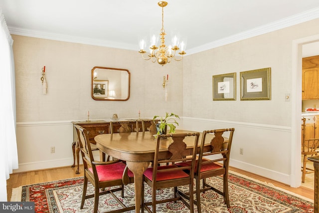 dining area with baseboards, ornamental molding, an inviting chandelier, and light wood-style floors