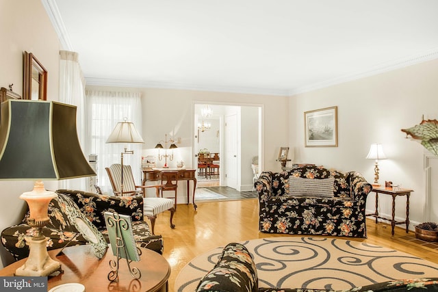 living area with ornamental molding, a chandelier, baseboards, and wood finished floors