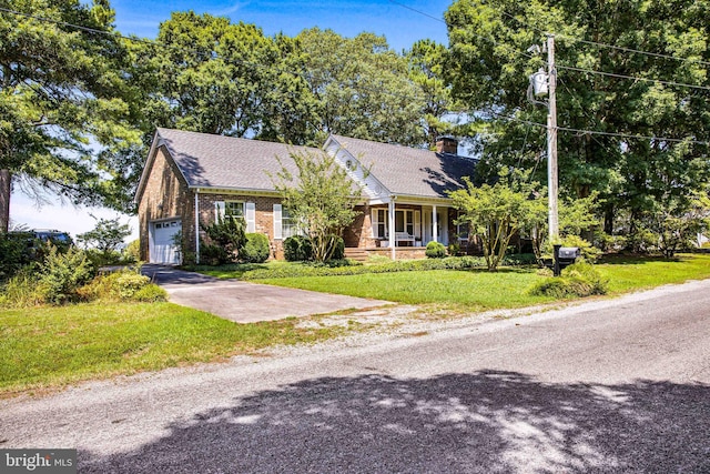 view of front of property featuring a chimney, covered porch, a garage, driveway, and a front lawn