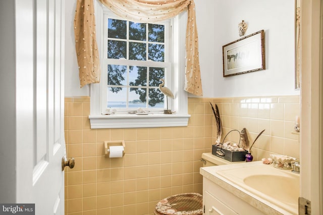 half bathroom with wainscoting, tile walls, and vanity