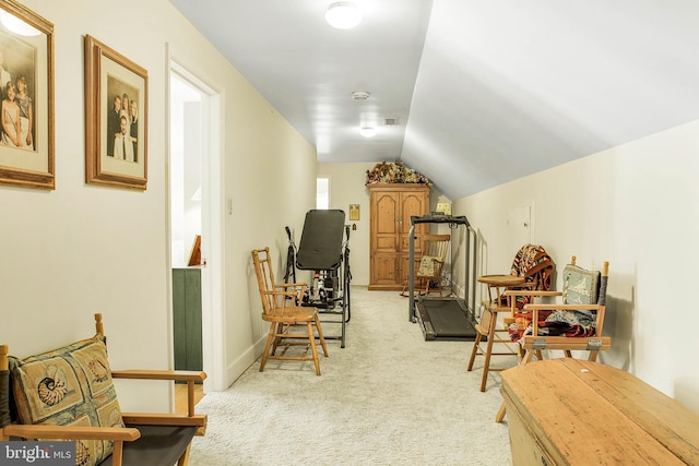 interior space featuring light carpet, vaulted ceiling, visible vents, and baseboards