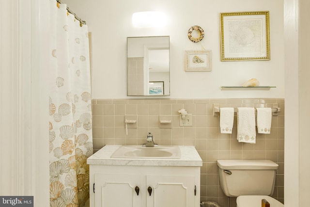 full bath featuring vanity, toilet, and tile walls