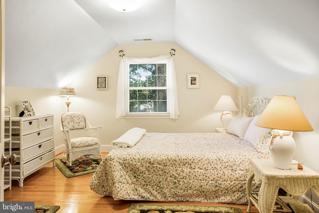 bedroom featuring vaulted ceiling, wood finished floors, visible vents, and baseboards