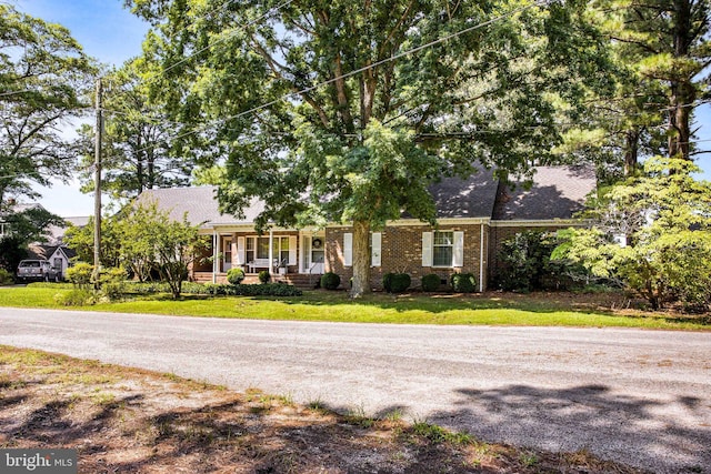 view of front of property with covered porch, a front lawn, and brick siding