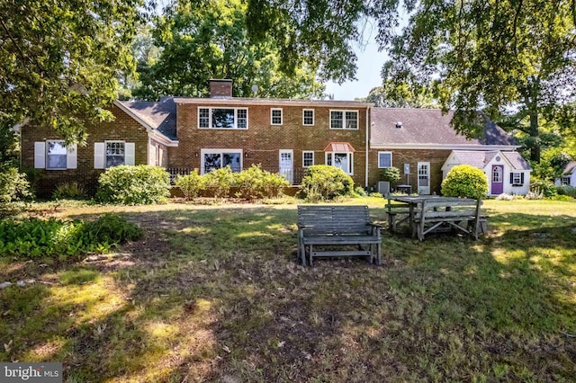 back of property with a yard, a chimney, and brick siding