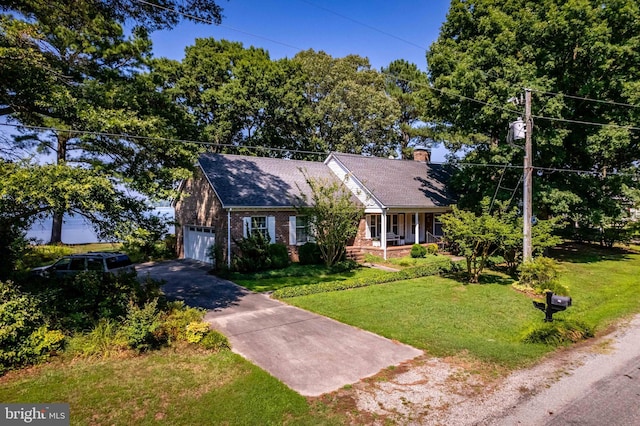 new england style home featuring driveway, a garage, a chimney, a front lawn, and brick siding