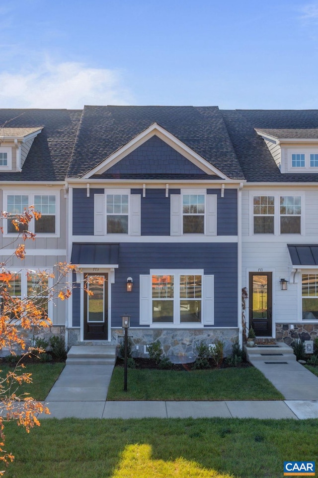 view of front of house featuring a shingled roof and a front lawn