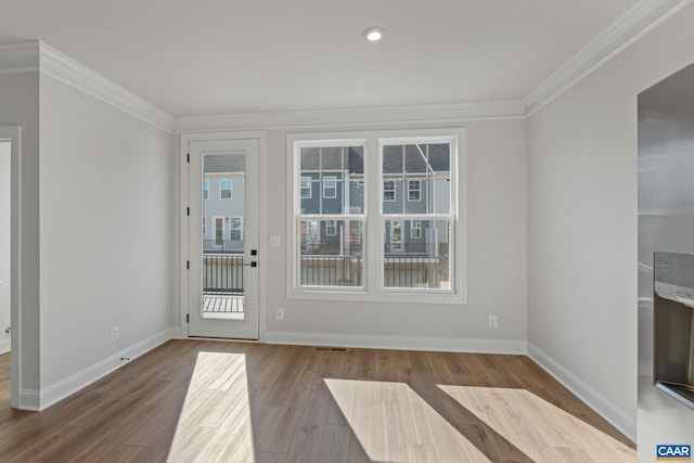 entryway with visible vents, baseboards, crown molding, and wood finished floors