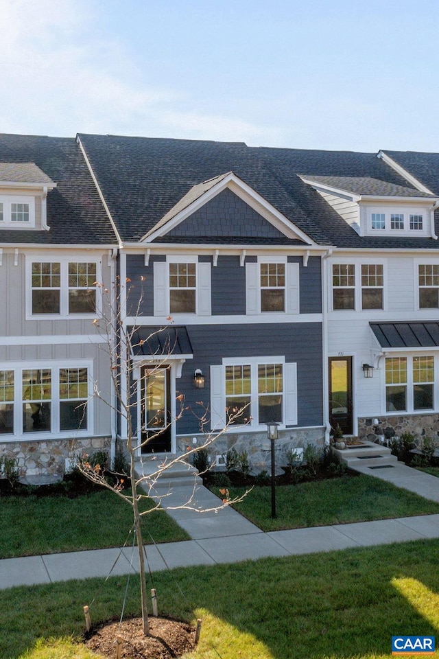 view of front of home with board and batten siding, a front yard, and a shingled roof