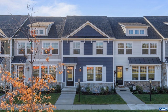 townhome / multi-family property with a standing seam roof, stone siding, metal roof, and roof with shingles