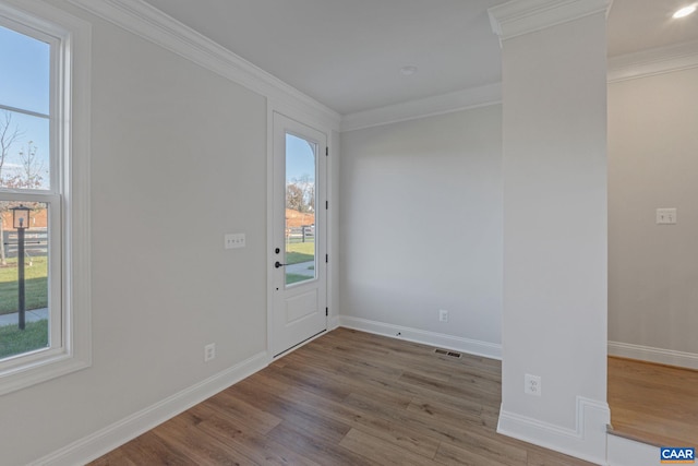 entrance foyer with ornamental molding, visible vents, baseboards, and wood finished floors