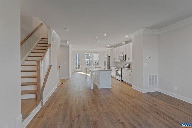 kitchen featuring stainless steel appliances, visible vents, light wood-style floors, white cabinets, and a sink