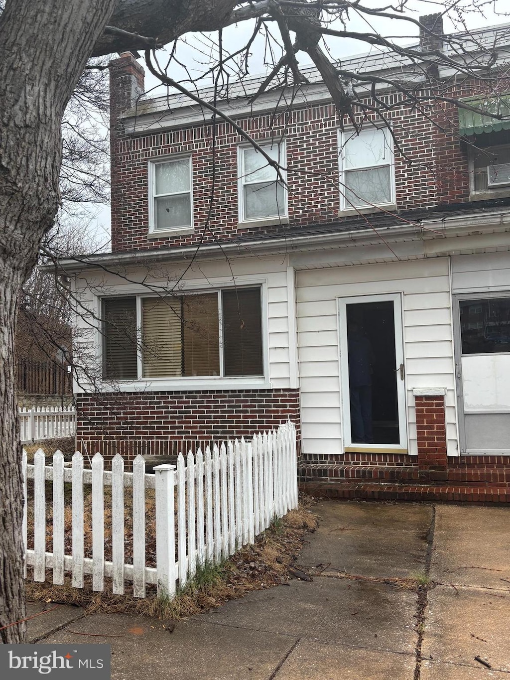 view of front of home with entry steps, a fenced front yard, and brick siding