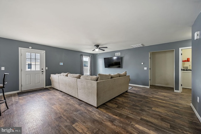 unfurnished living room with dark wood-style floors, a healthy amount of sunlight, and baseboards