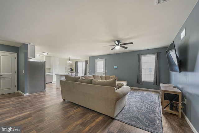 living room featuring baseboards, dark wood finished floors, and a healthy amount of sunlight