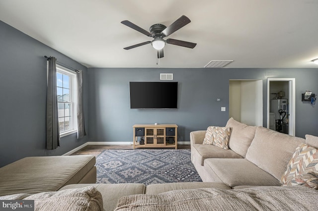 living area featuring baseboards, visible vents, and wood finished floors