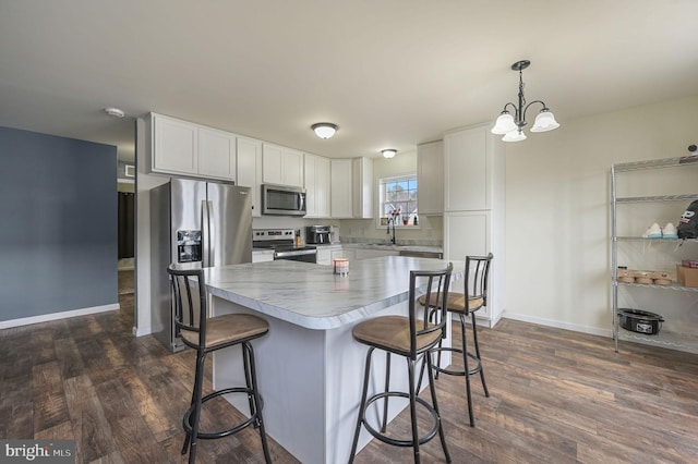 kitchen with white cabinetry, appliances with stainless steel finishes, a breakfast bar, and dark wood-style flooring