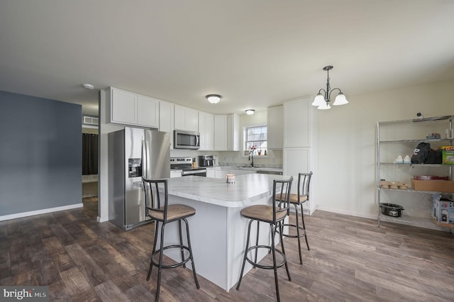 kitchen featuring appliances with stainless steel finishes, dark wood-style flooring, a breakfast bar, and white cabinets