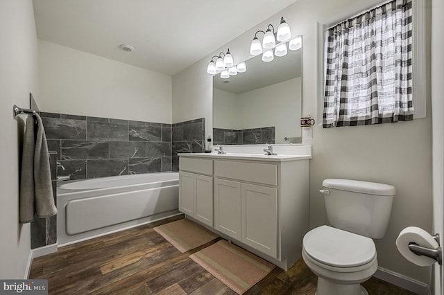 bathroom with baseboards, toilet, wood finished floors, a garden tub, and vanity