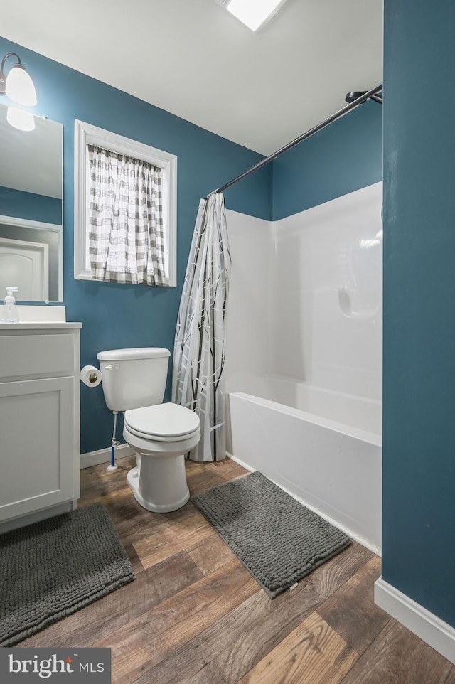 full bath featuring toilet, wood finished floors, vanity, baseboards, and shower / tub combo with curtain