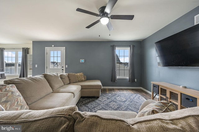 living room with ceiling fan, baseboards, and wood finished floors