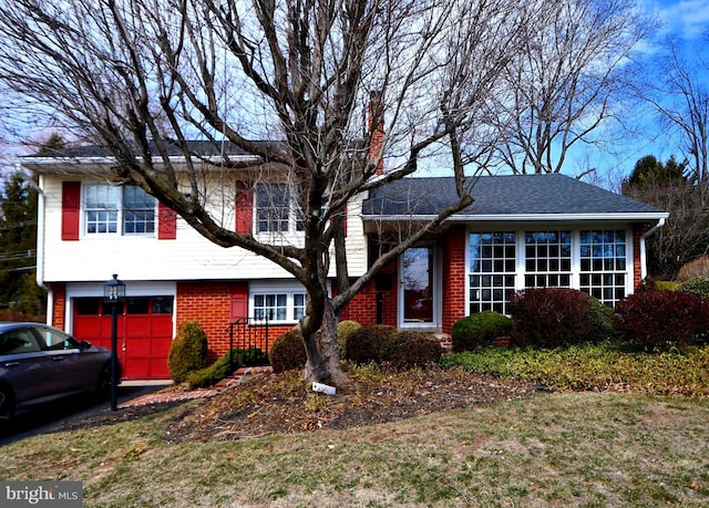 split level home featuring a garage, brick siding, and a chimney