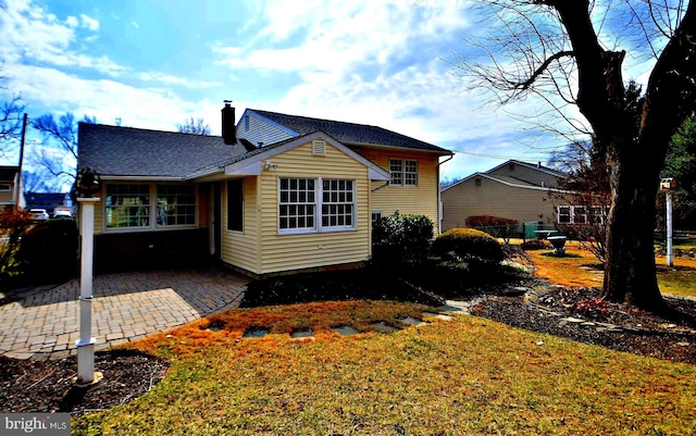 back of property with a shingled roof, a chimney, and a patio area