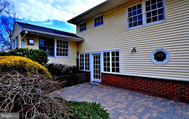 back of property with brick siding and a patio